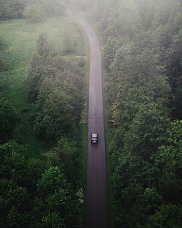 Samochód jadący drogą w pięknym zielonym lesie