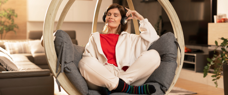Kobieta w mieszkaniu słucha muzyki na słuchawkach
