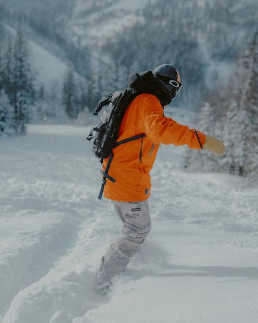 Kobieta w czerwonej czapce, stojąca na szczycie góry, patrząca w dal na widok