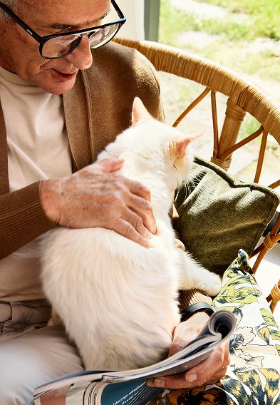 Mężczyzna czytający gazetę z kotem na rękach