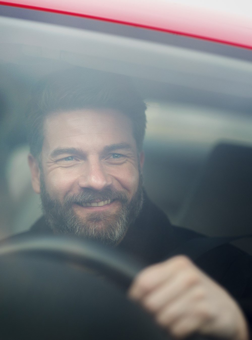 Mężczyzna siedzi w samochodzie uśmiechnięty