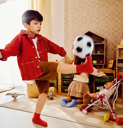 Chłopiec w czerwonej koszuli, bawi się w domu piłką