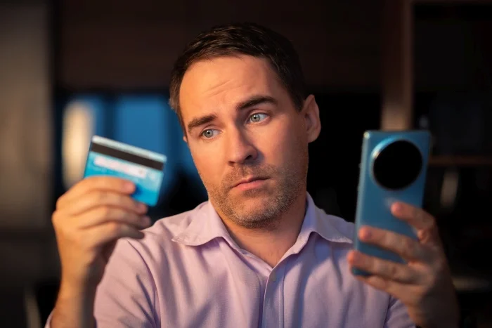 Mężczyzna trzymający kartę kredytową i telefon komórkowy w dłoni. Blog
