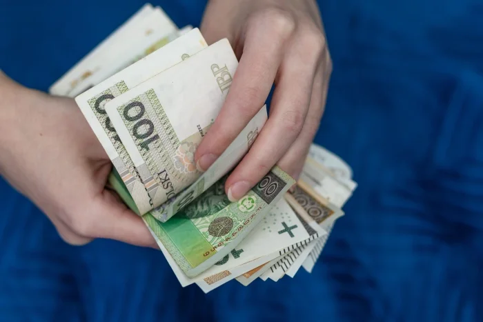 Ręce trzymające pakiet pieniędzy na niebieskim tle. Blog