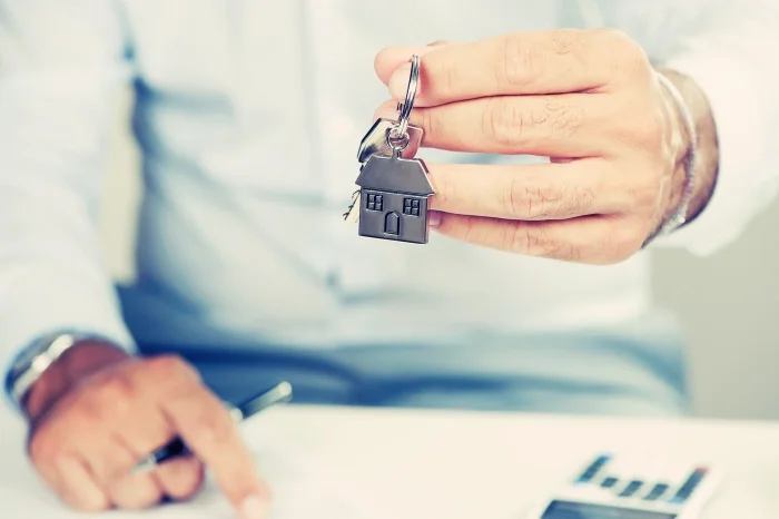 Mężczyzna trzymający brelok symbolizujący hipotekę, w tle wskazuje palcem na dokument. Blog