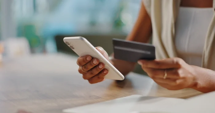 Postać trzymająca smartfon oraz kartę płatniczą. Blog