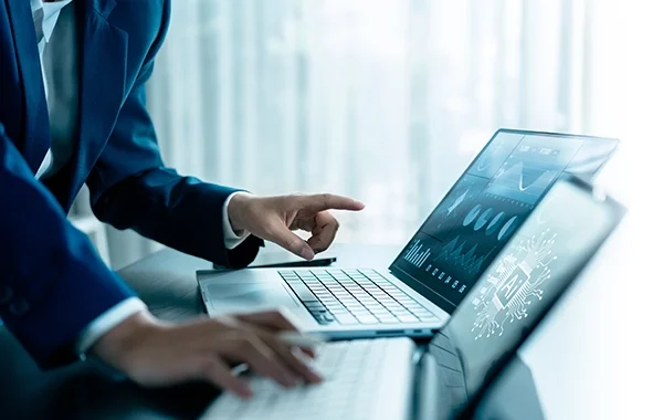 Ręce w garniturze pracujące na laptopie z wizualizacjami danych i motywem AI, nawiązujące do analizy Krajowego Rejestru Dłużników. Blog.