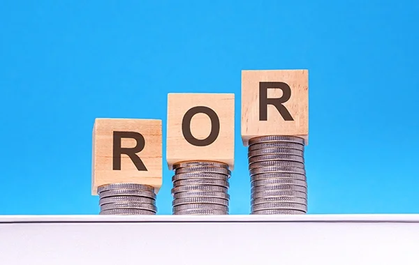 Trzy rosnące stosy monet z drewnianymi klockami oznaczonymi "R", "O", "R", symbolizujące korzyści z posiadania rachunku oszczędnościowo rozliczeniowego. Blog.