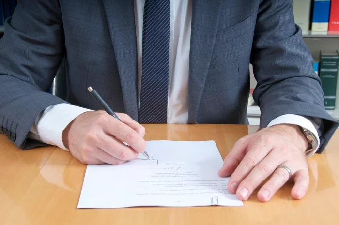 Mężczyzna w garniturze składający podpis na dokumencie. Blog